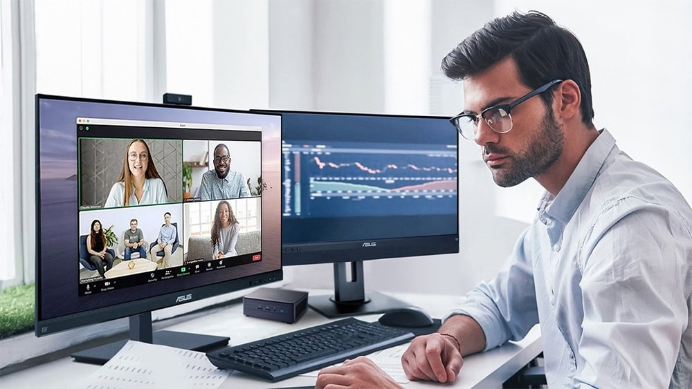 Çevrimiçi video konferans yapan genç adam, iki monitör ve dijital çizelgelerle masa başında çalışıyor, uzaktan çalışma ve iletişim teknikleri, teknoloji ve ofis ekipmanları konusu.
