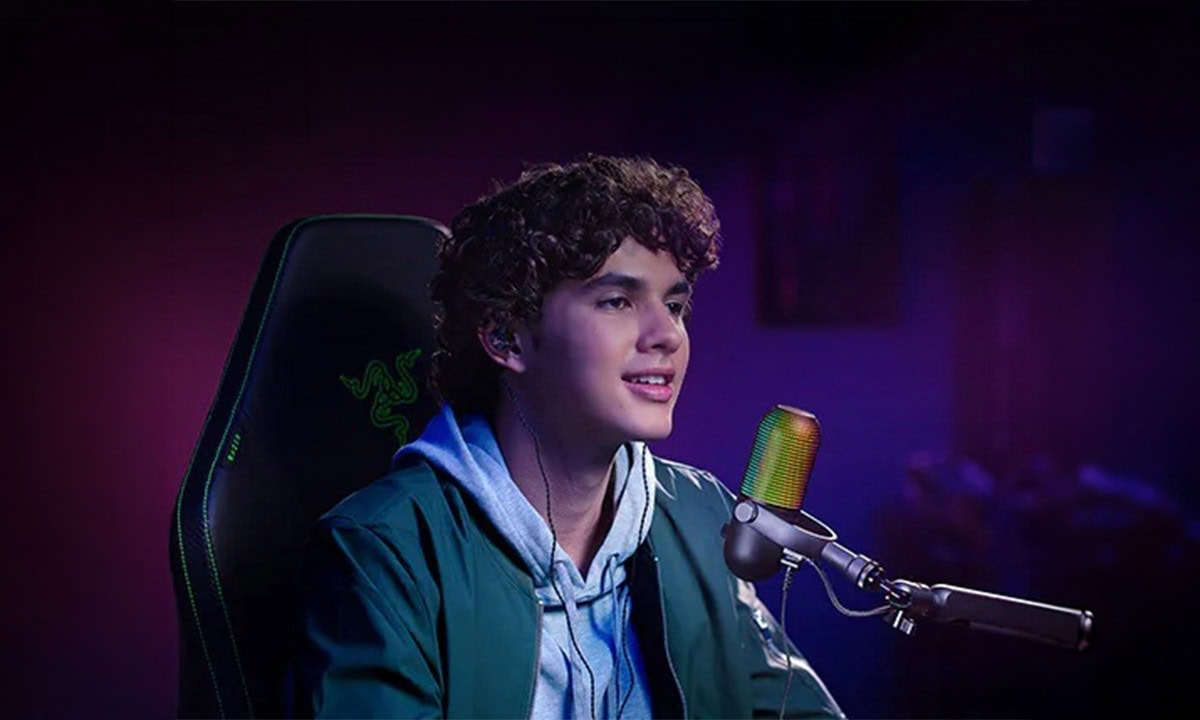 Genç yayıncı Razer Seiren V3 Chroma RGB süper kardioid kondansatör mikrofonu ile ses kaydı yapıyor. Profesyonel yayın ve içerik üretimi için ideal, RGB aydınlatmalı tasarım.