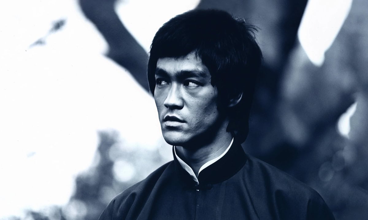 Bruce Lee'nin siyah beyaz portresi, ciddi ve odaklanmış ifadesiyle dikkat çekiyor.
